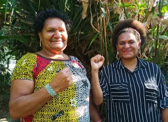 Two women from Papua New Guinea raise their fists
